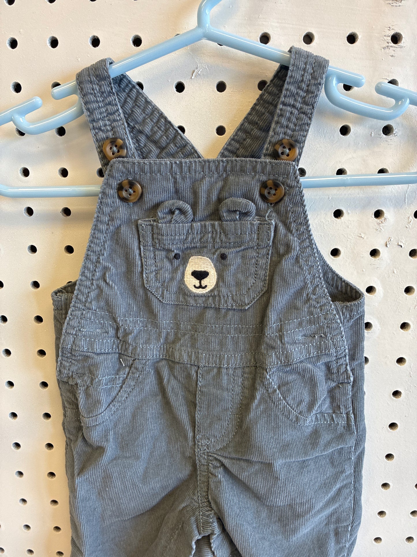 Newborn Carter's baby boy gray corduroy long overalls featuring a bear face design on the bib pocket
